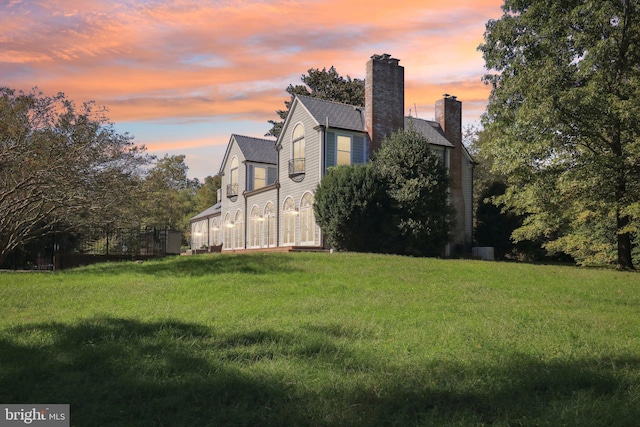 property exterior at dusk featuring a yard