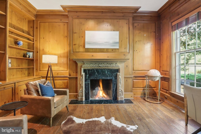 living area featuring a fireplace, wood walls, hardwood / wood-style floors, and a wealth of natural light