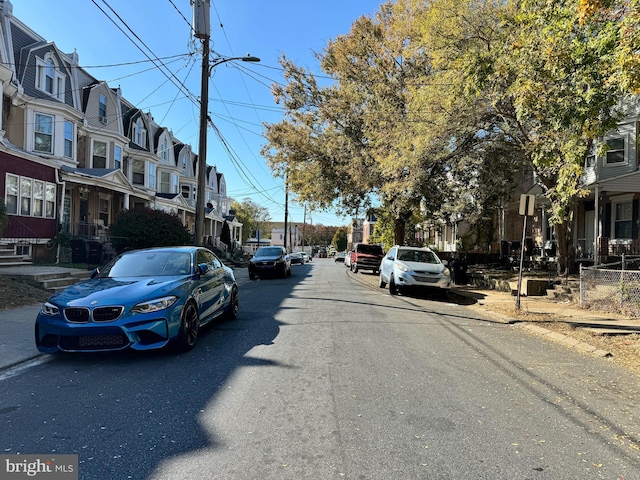 view of street featuring a residential view, sidewalks, curbs, and street lights