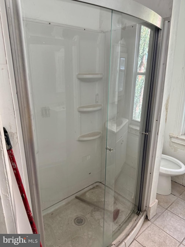 bathroom with a shower with shower door, toilet, and tile patterned flooring