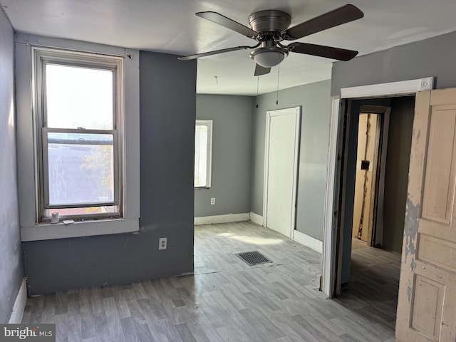 empty room featuring a wealth of natural light, light hardwood / wood-style floors, and ceiling fan