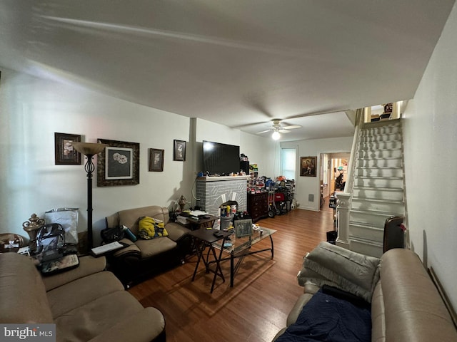 living room with a brick fireplace, hardwood / wood-style flooring, and ceiling fan