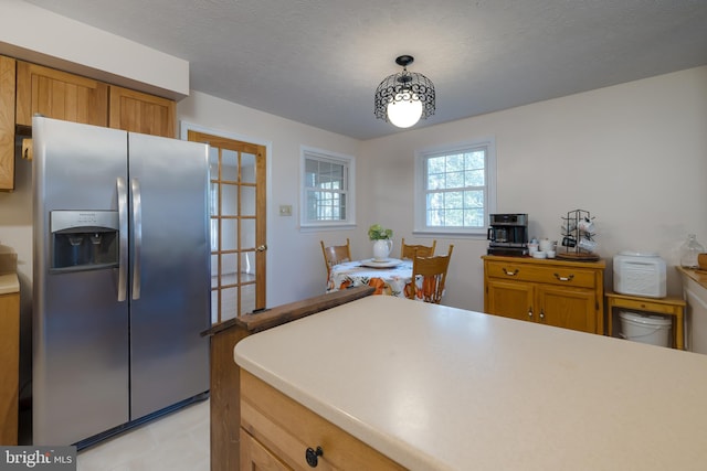 kitchen featuring pendant lighting, a textured ceiling, and stainless steel fridge with ice dispenser