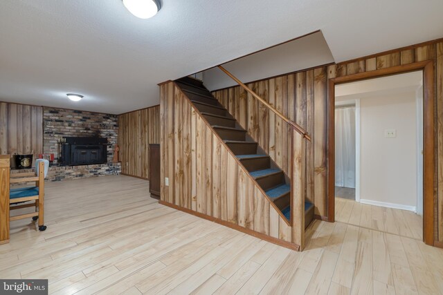 stairway with wooden walls, hardwood / wood-style floors, and a wood stove