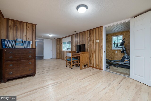 home office featuring wooden walls, light hardwood / wood-style floors, and a textured ceiling