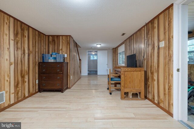 office with light wood-type flooring and wood walls