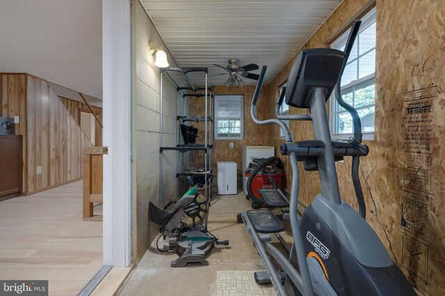 workout area featuring ceiling fan, wooden walls, and light hardwood / wood-style flooring