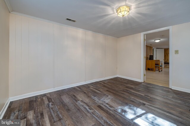 spare room featuring ornamental molding and dark wood-type flooring