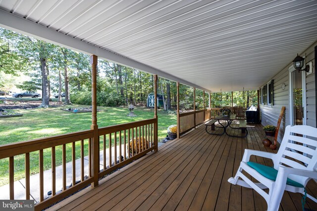 wooden deck with a shed and a lawn