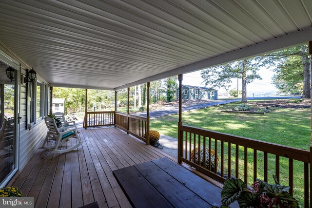 wooden terrace featuring a porch and a lawn