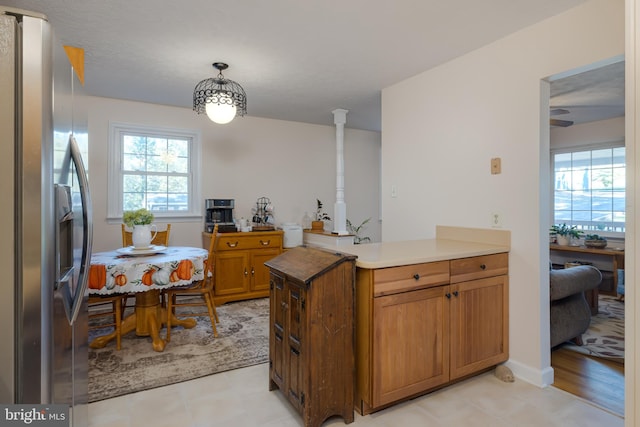 kitchen featuring light hardwood / wood-style floors, decorative light fixtures, kitchen peninsula, and stainless steel fridge with ice dispenser