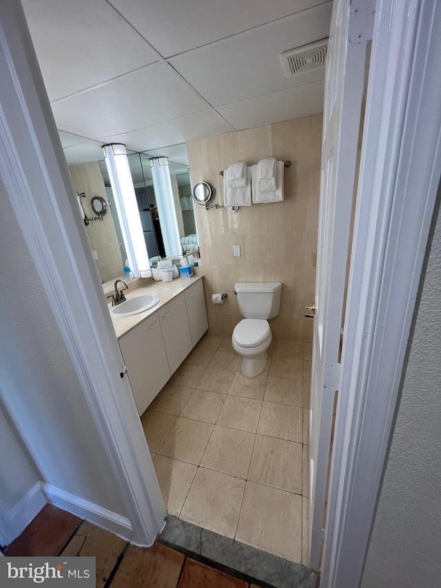 bathroom featuring vanity, tile walls, toilet, and tile patterned floors