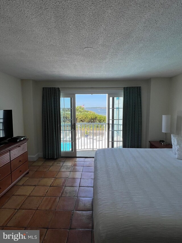 unfurnished bedroom featuring a textured ceiling, tile patterned floors, and access to outside