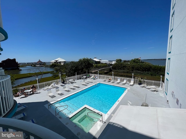 view of swimming pool featuring a water view and a patio area