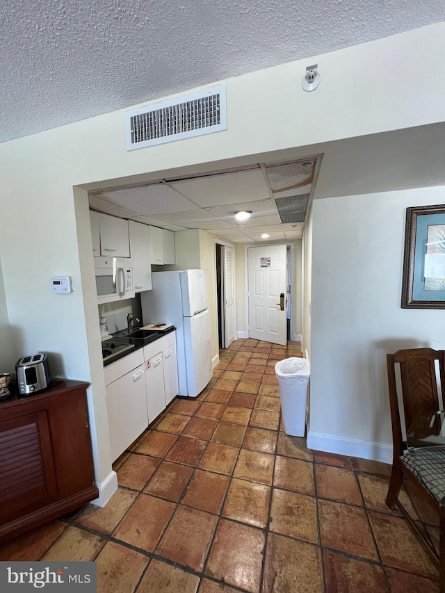 kitchen with white appliances, sink, and white cabinets