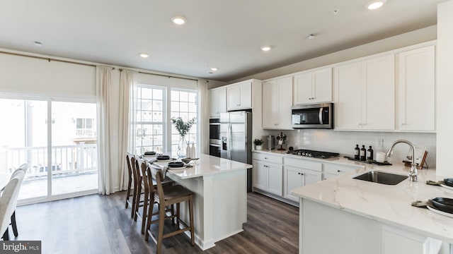 kitchen with sink, stainless steel appliances, dark hardwood / wood-style floors, a center island, and white cabinetry