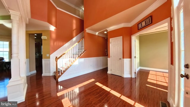 interior space with dark wood-type flooring, ornate columns, and ornamental molding