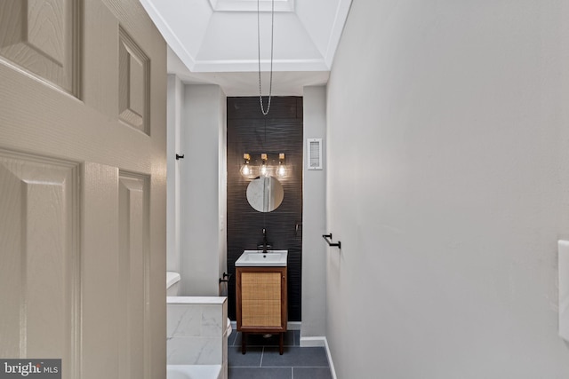 bathroom with tile patterned flooring, vanity, and a raised ceiling