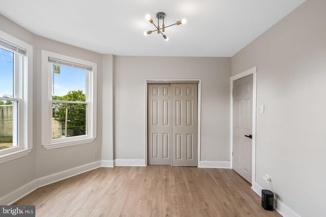 unfurnished bedroom with a chandelier, a closet, and light hardwood / wood-style floors