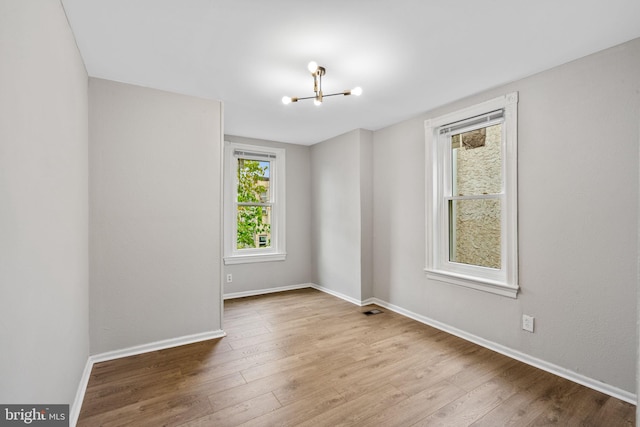 empty room with a notable chandelier and light wood-type flooring