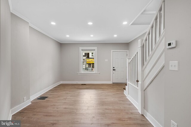 entrance foyer with ornamental molding and light hardwood / wood-style flooring