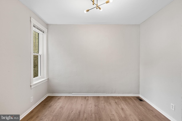 empty room featuring an inviting chandelier and light hardwood / wood-style flooring