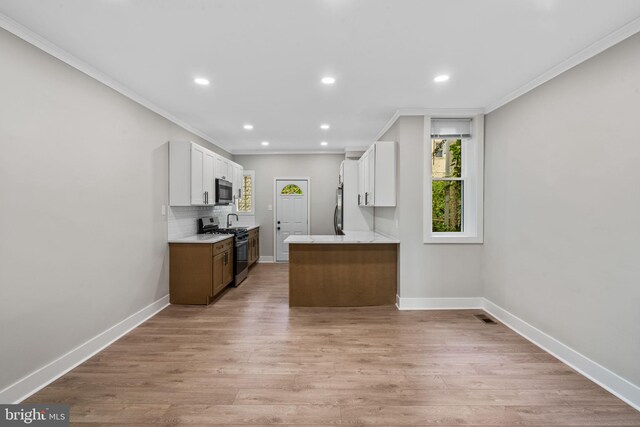 kitchen featuring tasteful backsplash, light hardwood / wood-style flooring, light stone counters, stainless steel appliances, and white cabinetry