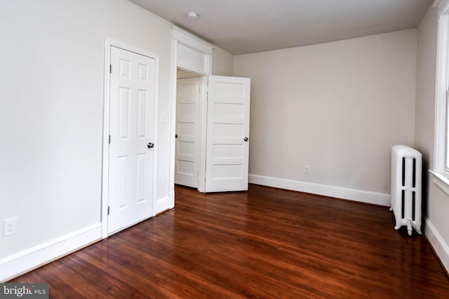 unfurnished bedroom with dark wood-type flooring and radiator