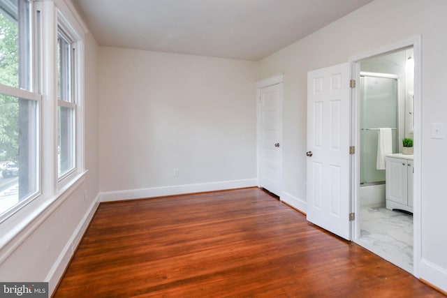 unfurnished bedroom featuring dark wood-type flooring and connected bathroom