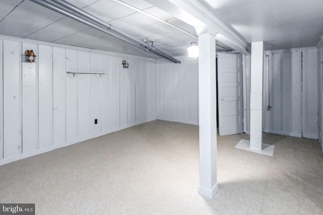 basement with wood walls and ornamental molding