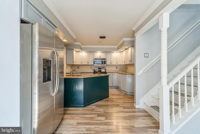 kitchen featuring light hardwood / wood-style floors, appliances with stainless steel finishes, ornamental molding, light stone countertops, and ornate columns