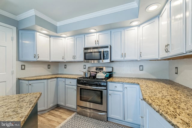 kitchen featuring crown molding, light wood-type flooring, appliances with stainless steel finishes, backsplash, and light stone countertops