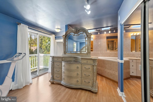 bathroom featuring track lighting, a bath, hardwood / wood-style flooring, and vanity