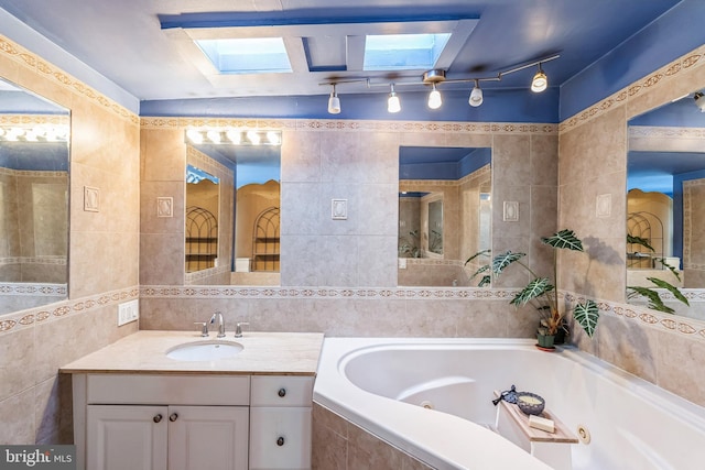 bathroom with tile walls, tiled bath, vanity, and a skylight