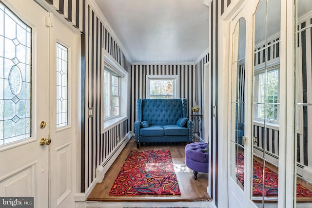 interior space with baseboard heating, hardwood / wood-style flooring, and ornamental molding