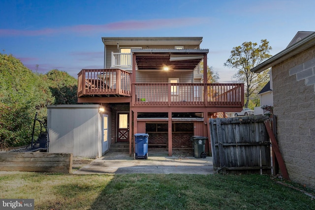 back house at dusk featuring a wooden deck and a lawn