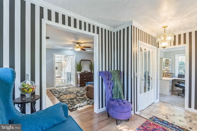 interior space with ornamental molding, light hardwood / wood-style floors, and ceiling fan with notable chandelier