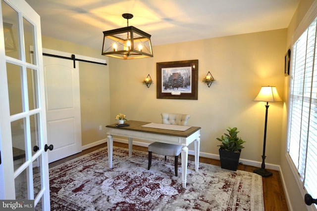 office featuring hardwood / wood-style floors, a barn door, and an inviting chandelier