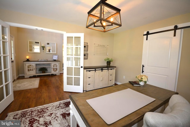 dining room with french doors, dark wood-type flooring, a barn door, and a chandelier