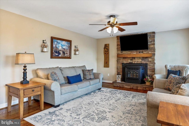 living room with wood-type flooring, ceiling fan, and a fireplace