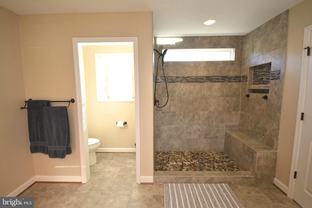 bathroom featuring tile patterned flooring, tiled shower, and toilet