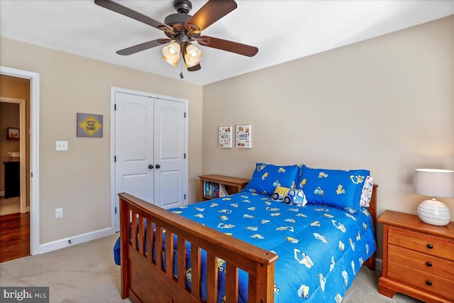 carpeted bedroom with ceiling fan and a closet