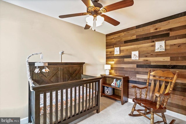 carpeted bedroom featuring wooden walls and a crib