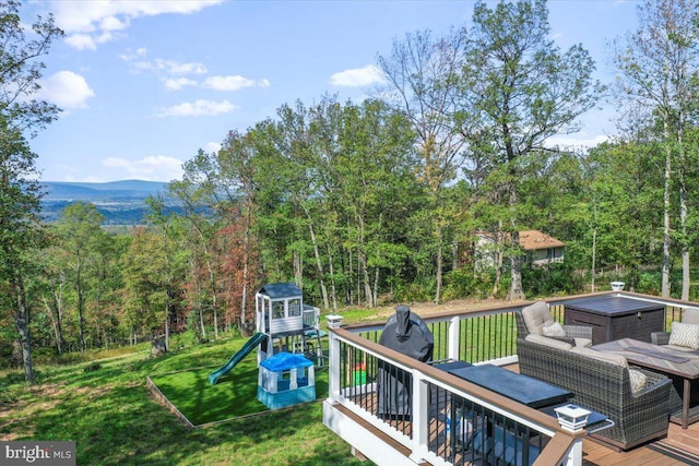 wooden deck with a playground, a lawn, and a mountain view