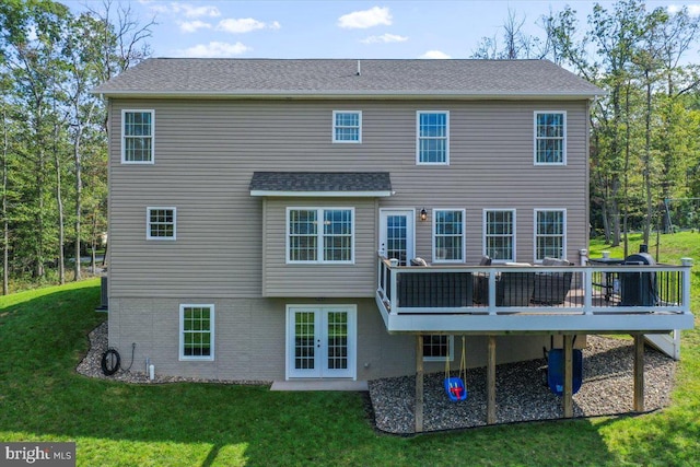 rear view of house with french doors, a wooden deck, and a lawn