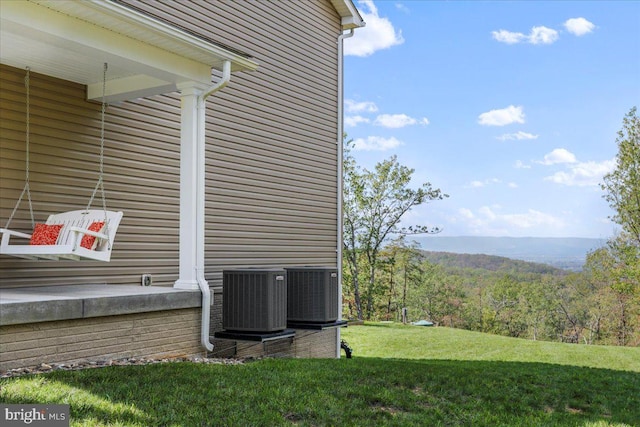 view of side of home with central AC unit and a lawn