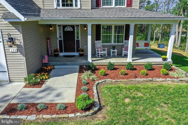 view of exterior entry with a lawn and covered porch