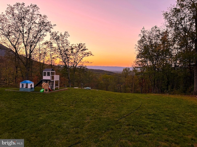 yard at dusk featuring a playground