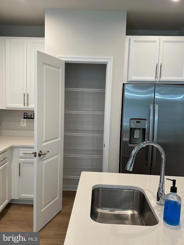 kitchen featuring white cabinetry, dark hardwood / wood-style flooring, sink, and stainless steel fridge