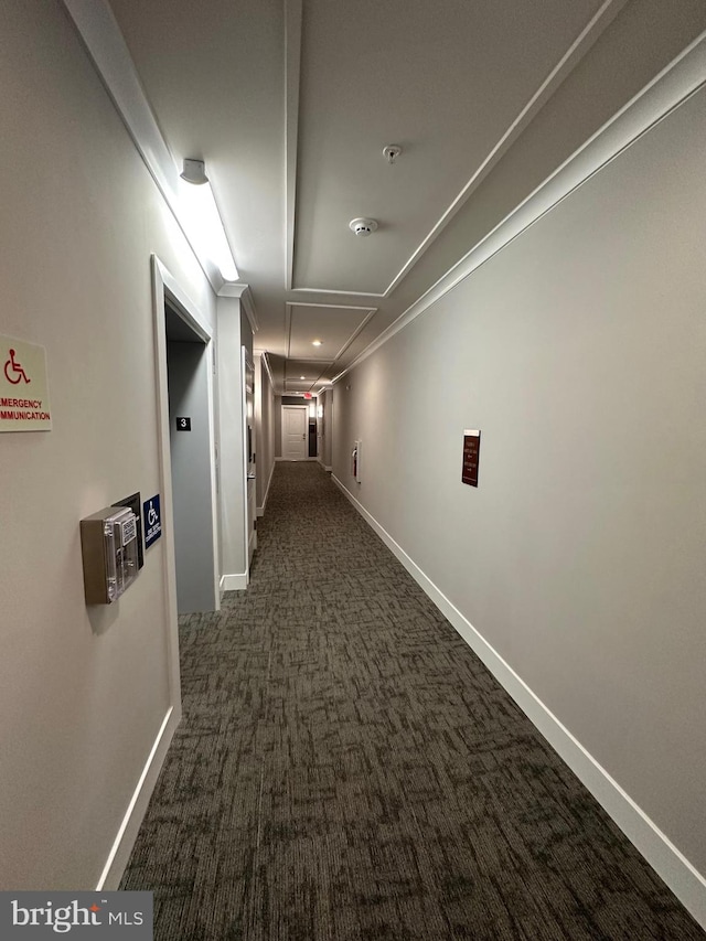 hallway featuring ornamental molding and dark colored carpet